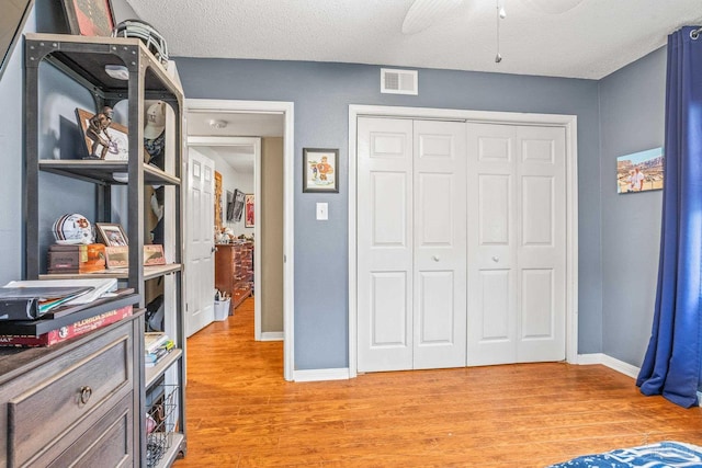2803 Venetian Way, Gulf Breeze, FL 32563 - bedroom featuring light wood-style floors, baseboards, a closet, ceiling fan, and a textured ceiling