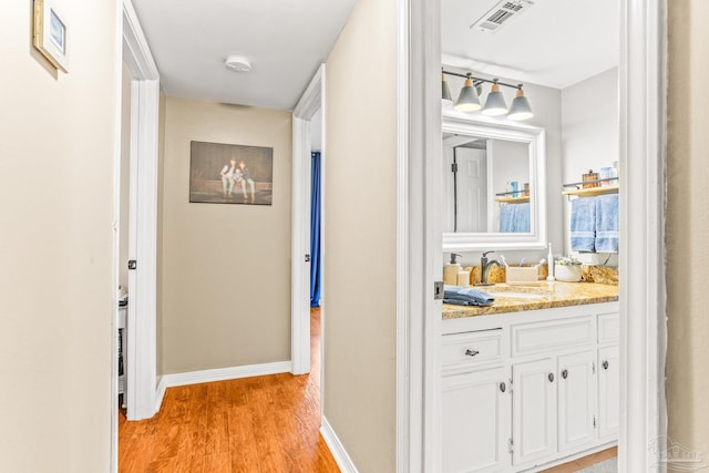 2803 Venetian Way, Gulf Breeze, FL 32563 - hallway with a sink, light wood-style floors, and baseboards