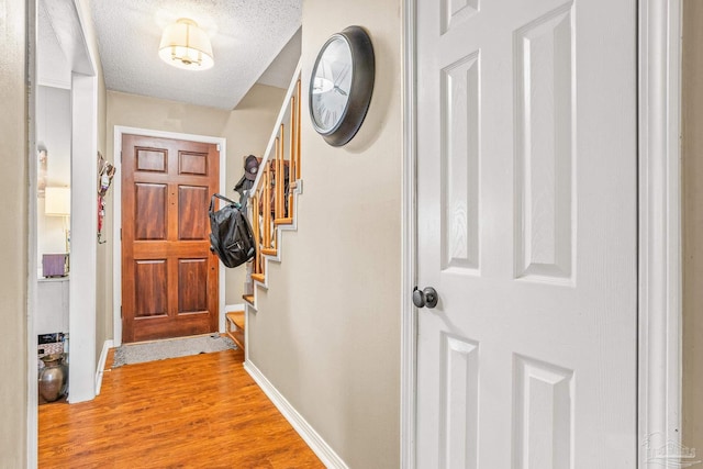 2803 Venetian Way, Gulf Breeze, FL 32563 - doorway with light wood finished floors, baseboards, a textured ceiling, and stairs