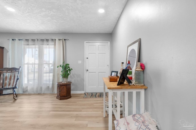 foyer featuring a textured ceiling, light wood-type flooring, and baseboards