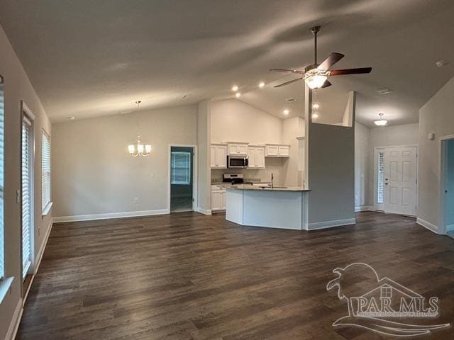 unfurnished living room with ceiling fan with notable chandelier, dark wood-type flooring, and high vaulted ceiling