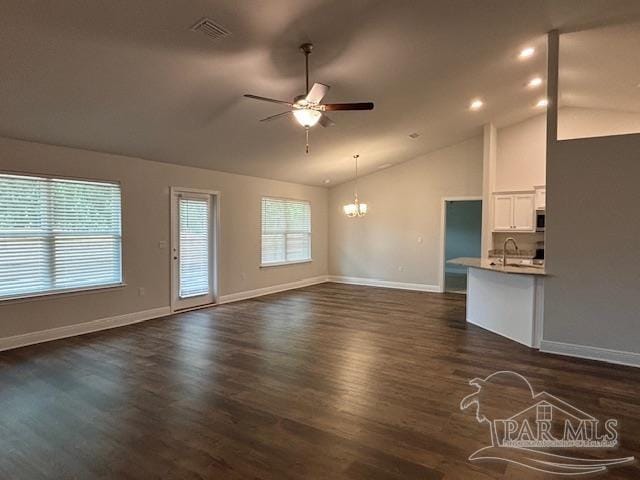 unfurnished living room featuring vaulted ceiling, sink, dark wood-type flooring, and ceiling fan with notable chandelier