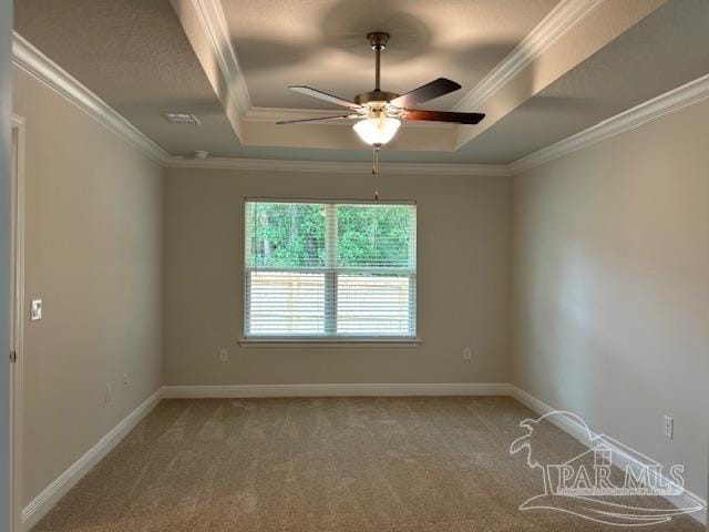 carpeted spare room featuring a tray ceiling, ornamental molding, and ceiling fan