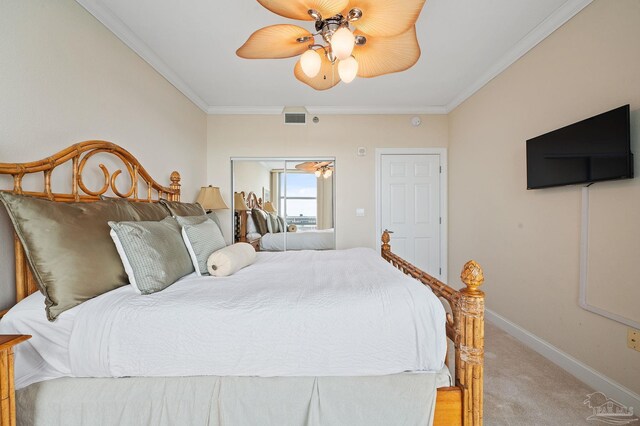 carpeted bedroom with ceiling fan, a closet, and crown molding