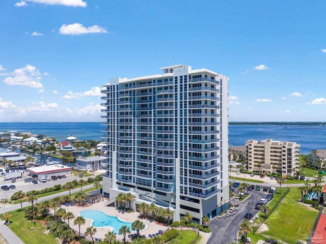 view of building exterior featuring a community pool and a water view