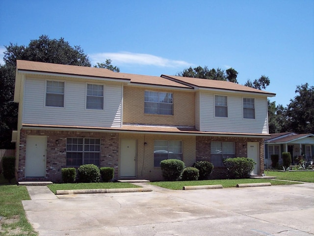 multi unit property featuring brick siding and a front lawn