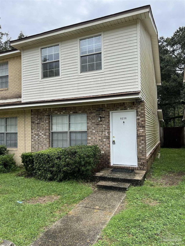 view of front of home with a front yard and brick siding