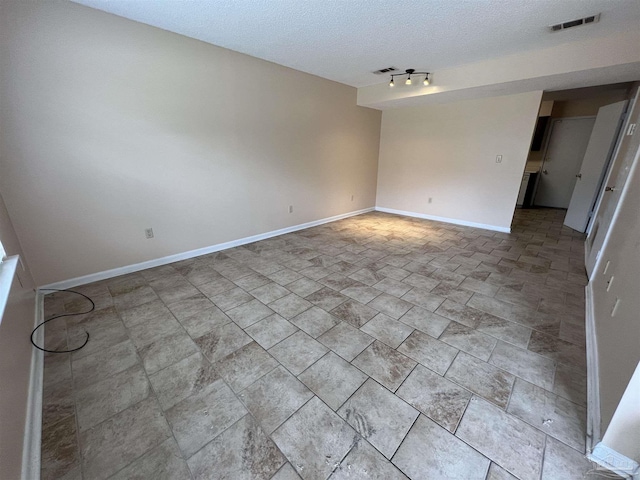 unfurnished room with baseboards, visible vents, and a textured ceiling