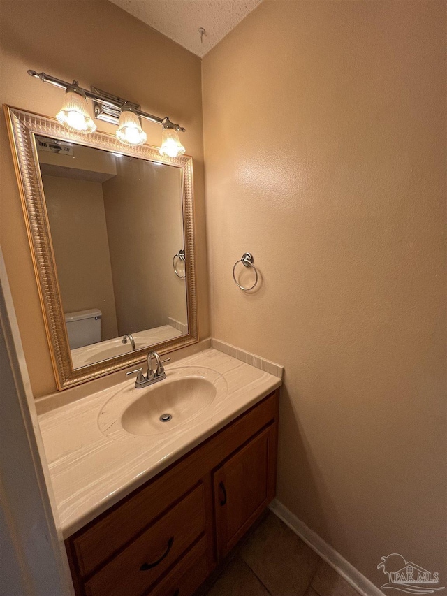 bathroom featuring toilet, tile patterned floors, baseboards, and vanity