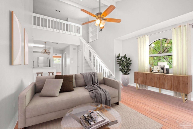 living room with ceiling fan, wood-type flooring, and a high ceiling