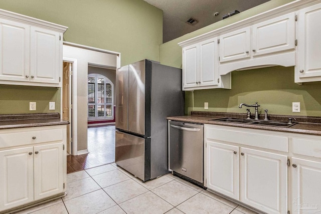 kitchen with sink, white cabinets, light tile patterned floors, and appliances with stainless steel finishes