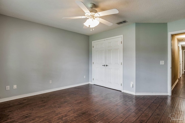 unfurnished bedroom with a textured ceiling, a closet, ceiling fan, and dark wood-type flooring