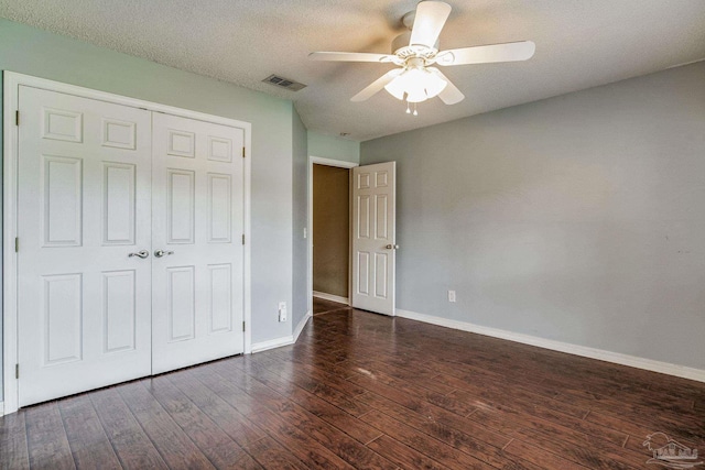 unfurnished bedroom with ceiling fan, dark hardwood / wood-style flooring, a textured ceiling, and a closet