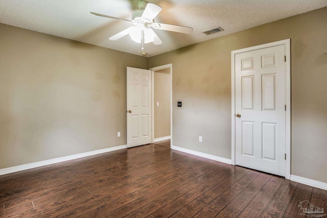 empty room featuring dark hardwood / wood-style floors, ceiling fan, and a textured ceiling