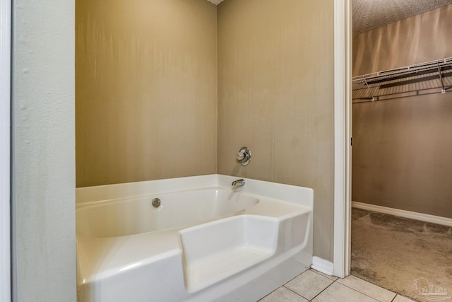 bathroom featuring tile patterned flooring, a bath, and a textured ceiling