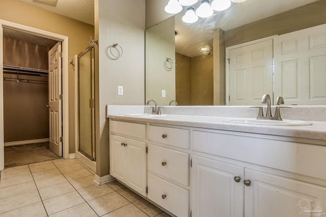 bathroom featuring a textured ceiling, tile patterned flooring, vanity, and an enclosed shower