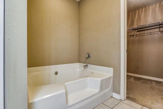 bathroom with tile patterned flooring, a textured ceiling, and a washtub