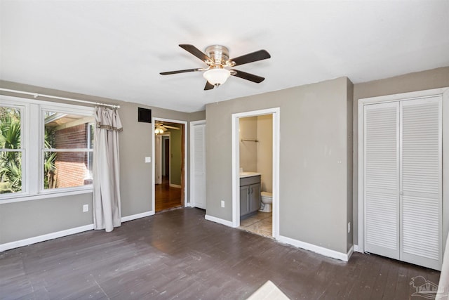 unfurnished bedroom featuring ensuite bath, dark hardwood / wood-style flooring, and ceiling fan