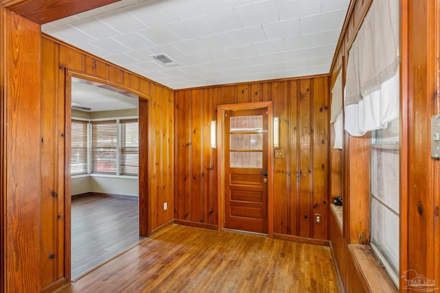 foyer featuring crown molding, wood walls, and light wood-type flooring