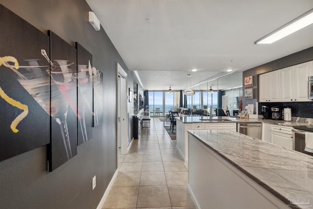 kitchen featuring light tile patterned floors, appliances with stainless steel finishes, white cabinetry, and a peninsula