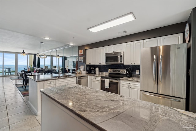 kitchen with visible vents, backsplash, appliances with stainless steel finishes, a peninsula, and white cabinets