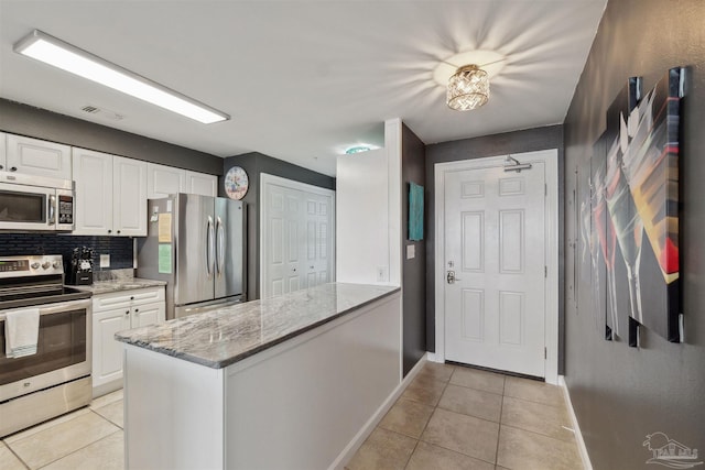 kitchen featuring light tile patterned floors, appliances with stainless steel finishes, and white cabinetry