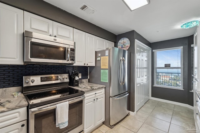 kitchen featuring visible vents, light tile patterned floors, decorative backsplash, stainless steel appliances, and white cabinetry