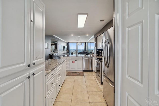 kitchen featuring light tile patterned floors, visible vents, a peninsula, stainless steel appliances, and white cabinetry