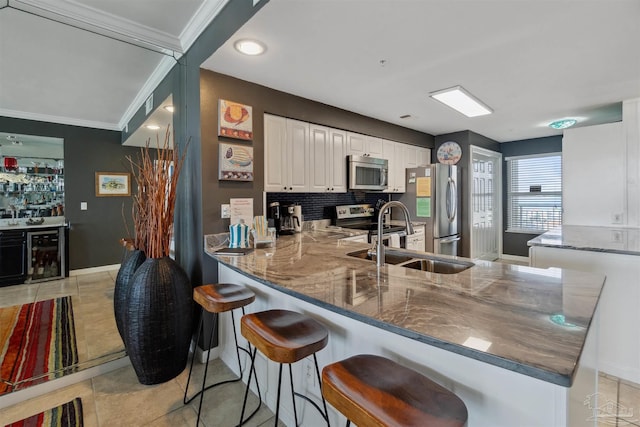 kitchen with a peninsula, dark stone counters, beverage cooler, and stainless steel appliances