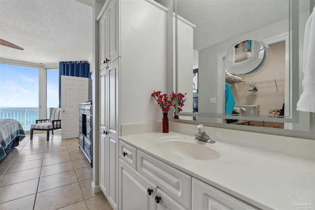 bathroom with tile patterned floors, a water view, a textured ceiling, floor to ceiling windows, and vanity