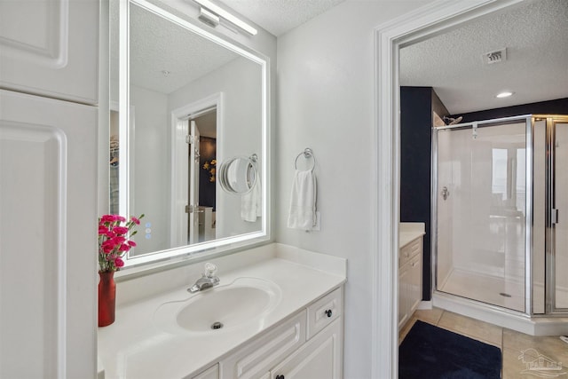 bathroom with tile patterned floors, visible vents, a stall shower, and vanity