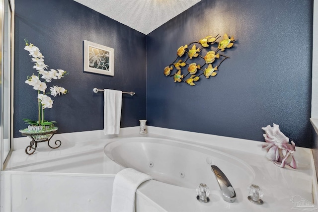 bathroom featuring a jetted tub and a textured wall