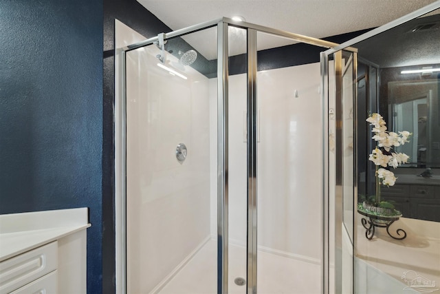 bathroom with a shower stall, a textured ceiling, vanity, and a textured wall