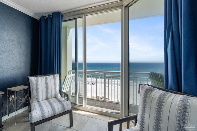 interior space featuring tile patterned flooring, a beach view, a healthy amount of sunlight, and a water view