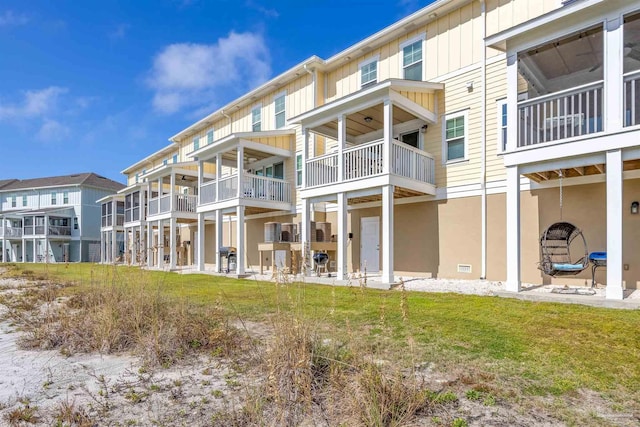 rear view of property with a yard, a patio area, and a balcony