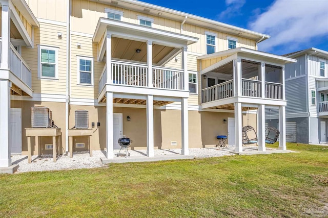 back of house with a sunroom, a balcony, a yard, and a patio