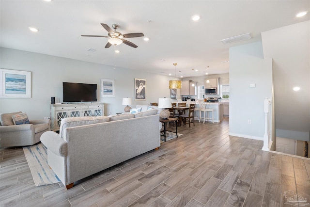 living room featuring light hardwood / wood-style floors and ceiling fan