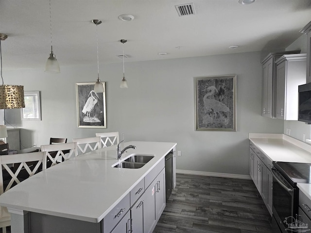 kitchen featuring gray cabinetry, pendant lighting, sink, an island with sink, and dark hardwood / wood-style flooring