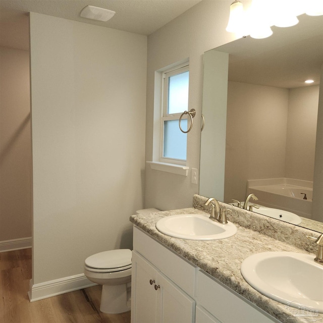 bathroom featuring vanity, hardwood / wood-style flooring, toilet, and a bathing tub