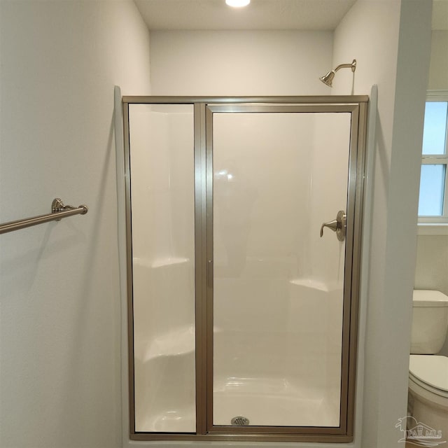 bathroom featuring an enclosed shower and toilet