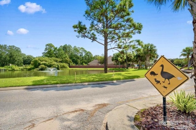 surrounding community with a water view and a yard