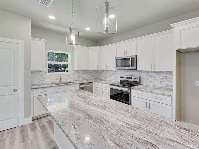 5773 Trevino Dr, Milton, FL 32570 - kitchen featuring stainless steel appliances, a sink, white cabinets, light stone countertops, and tasteful backsplash