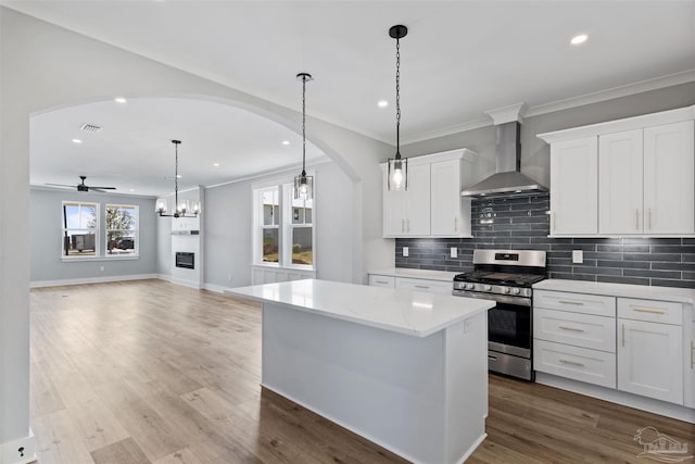 9616 Indian Stone Ct Lot 8, Navarre, FL 32566 - kitchen with wall chimney range hood, a ceiling fan, arched walkways, gas stove, and a center island