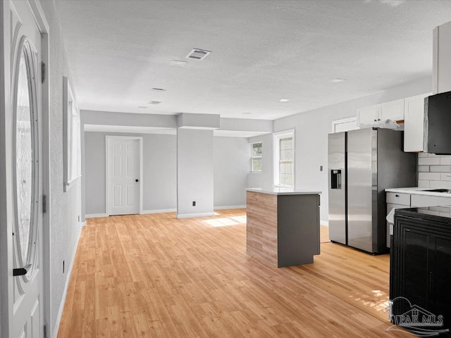 kitchen with light wood-style floors, light countertops, backsplash, and stainless steel fridge with ice dispenser