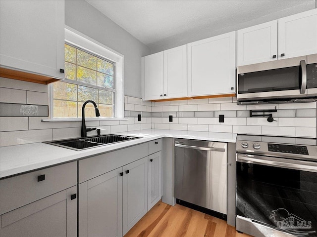 kitchen featuring tasteful backsplash, appliances with stainless steel finishes, light countertops, and a sink