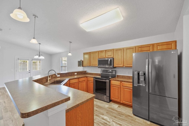 kitchen featuring light hardwood / wood-style floors, vaulted ceiling, sink, hanging light fixtures, and appliances with stainless steel finishes