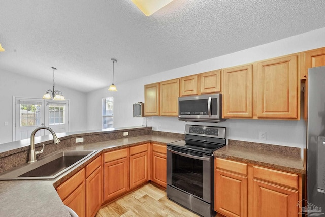 kitchen with pendant lighting, sink, stainless steel appliances, light wood-type flooring, and vaulted ceiling