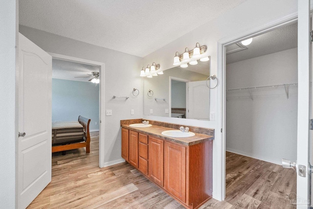 bathroom with wood-type flooring, vanity, a textured ceiling, and ceiling fan