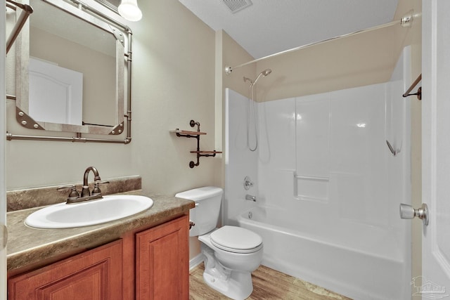 full bathroom featuring vanity, bathing tub / shower combination, hardwood / wood-style flooring, toilet, and a textured ceiling