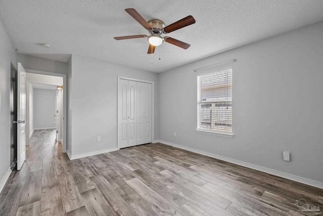 unfurnished bedroom featuring ceiling fan, a closet, light hardwood / wood-style floors, and a textured ceiling